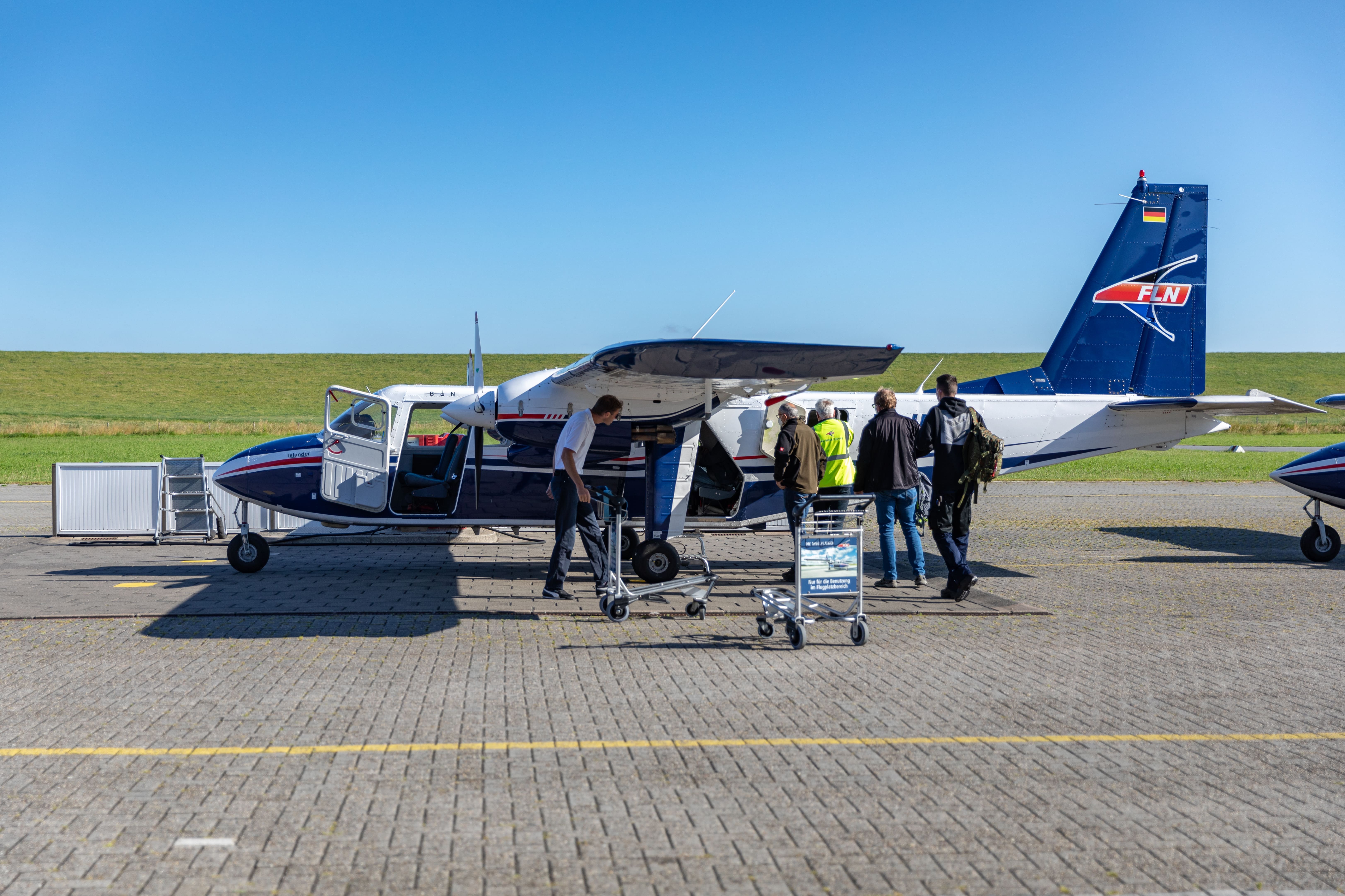 Ansicht des Inselfliegers von der Seite. Mehrere Personen sind dabei einzusteigen.